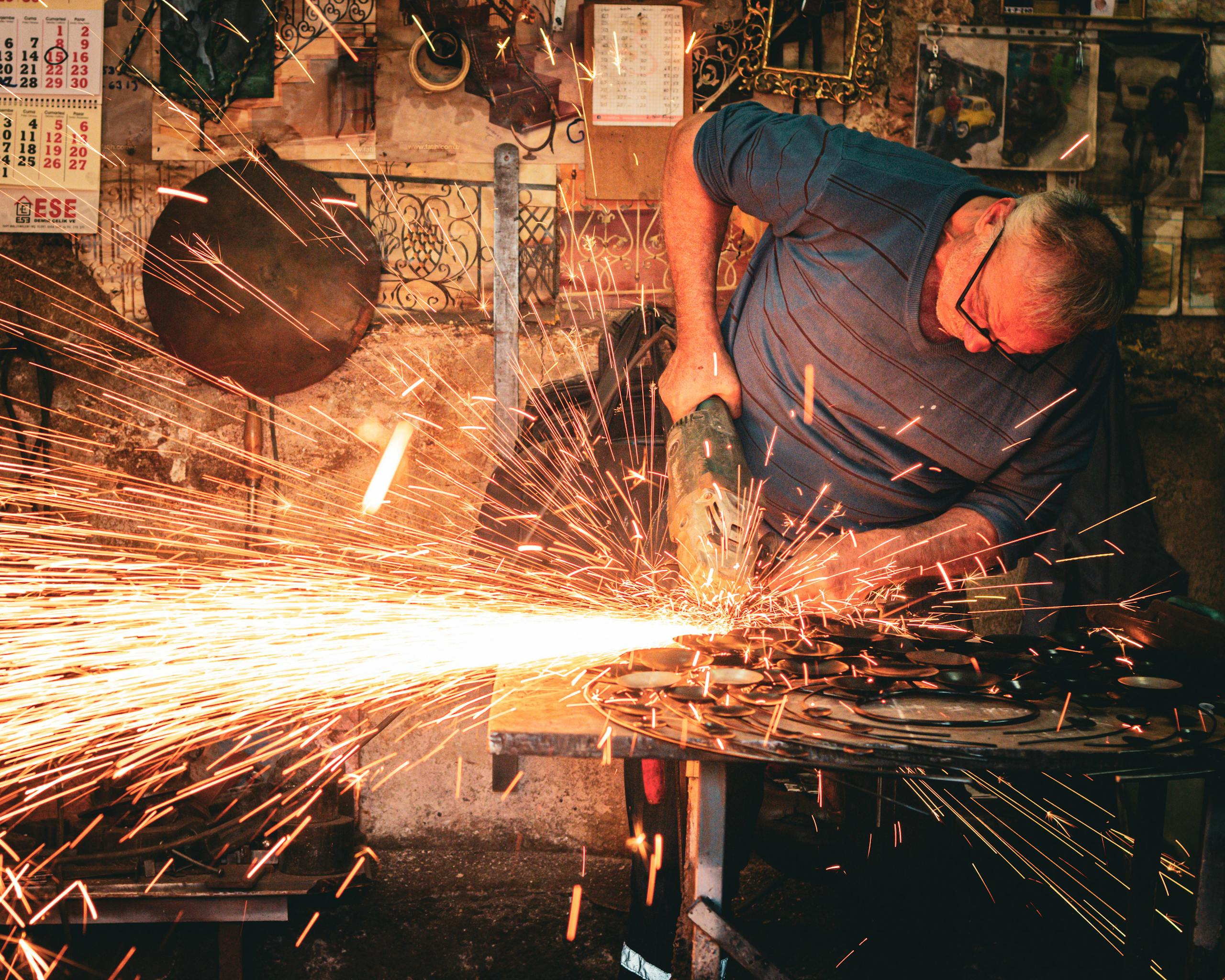 A craftsman skillfully uses a grinder in a workshop, generating a bright shower of sparks.