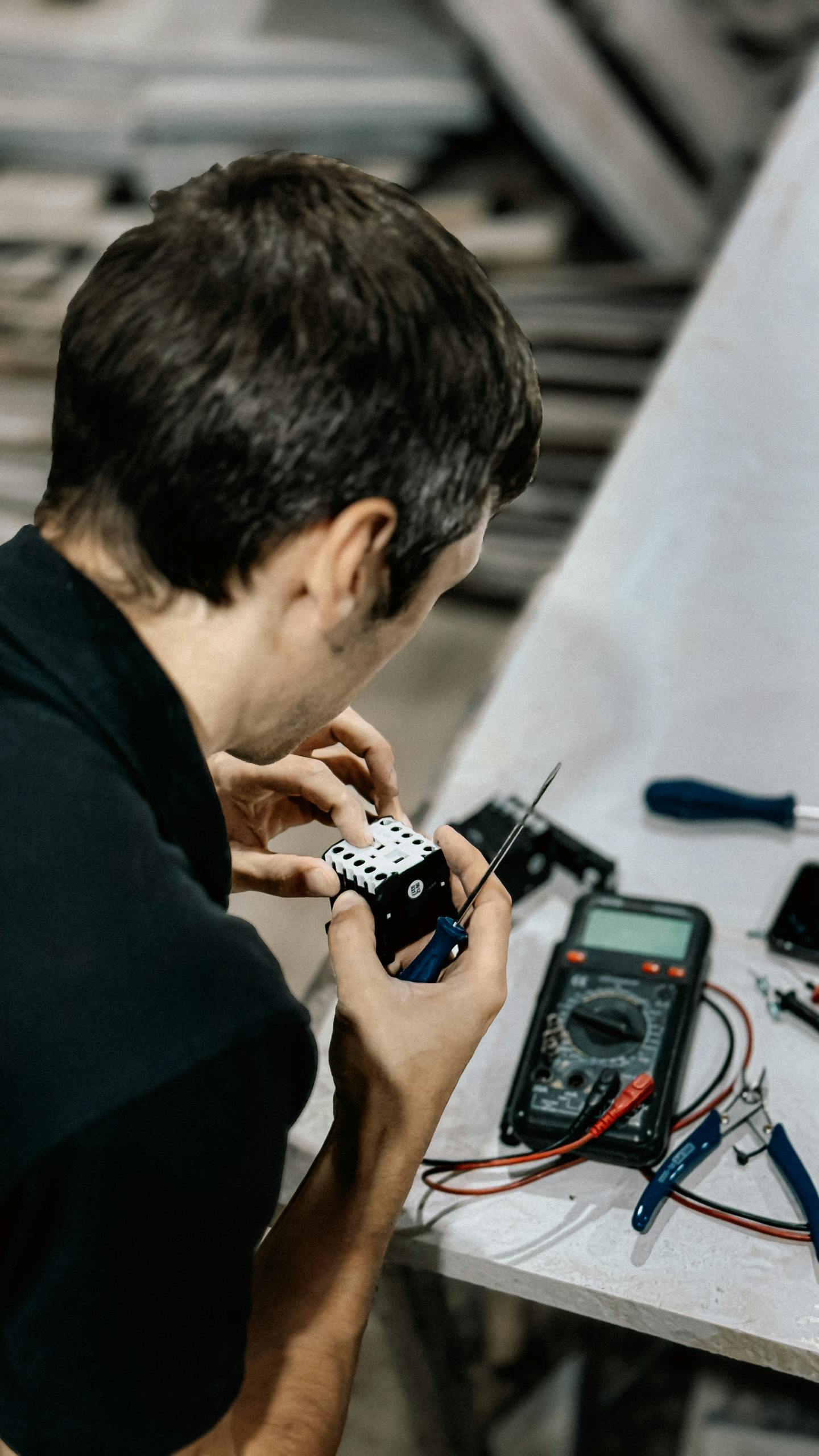 Adult male technician working on electronic circuit board in workshop.