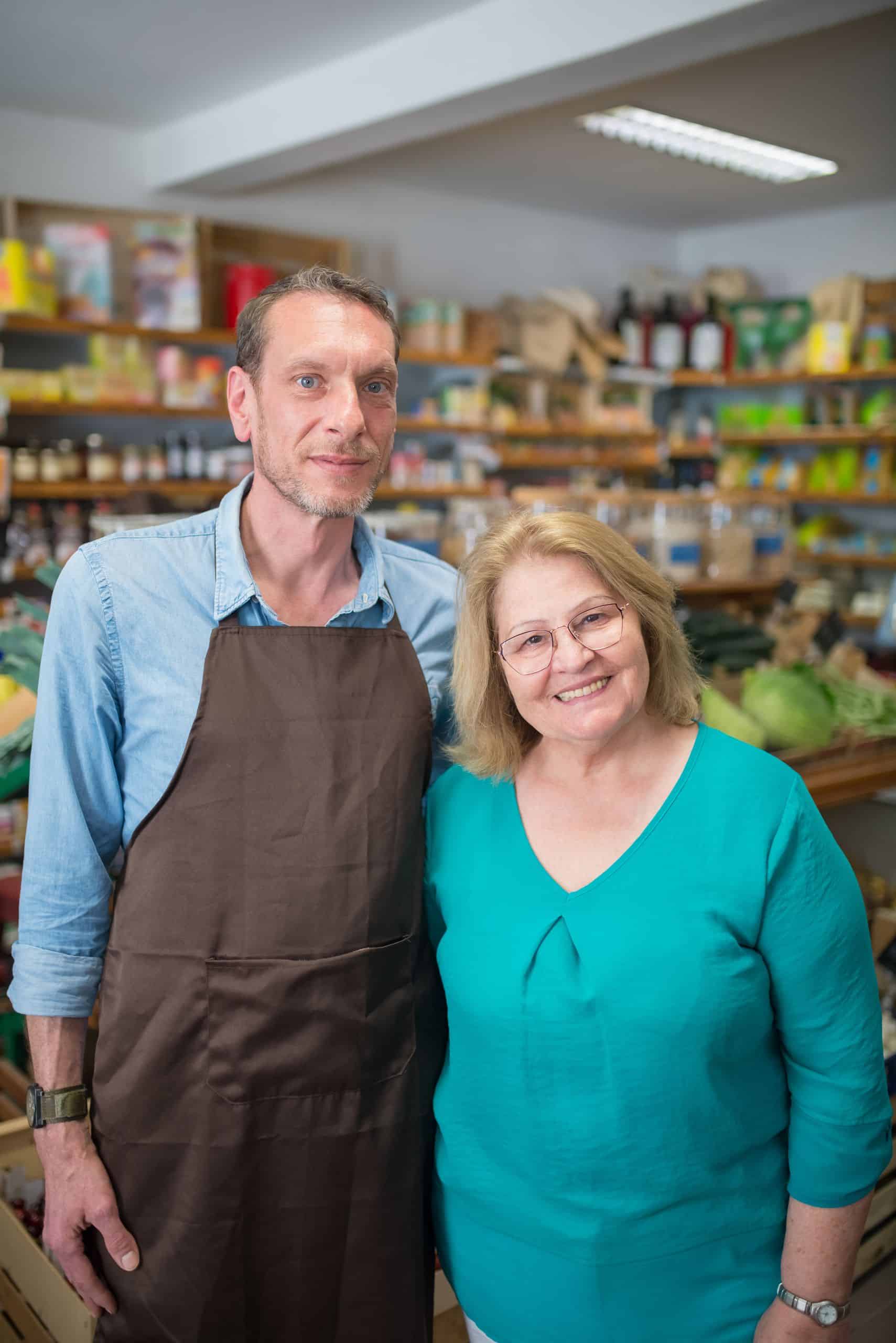 Friendly store clerks posing with smiles inside a well-stocked grocery shop.